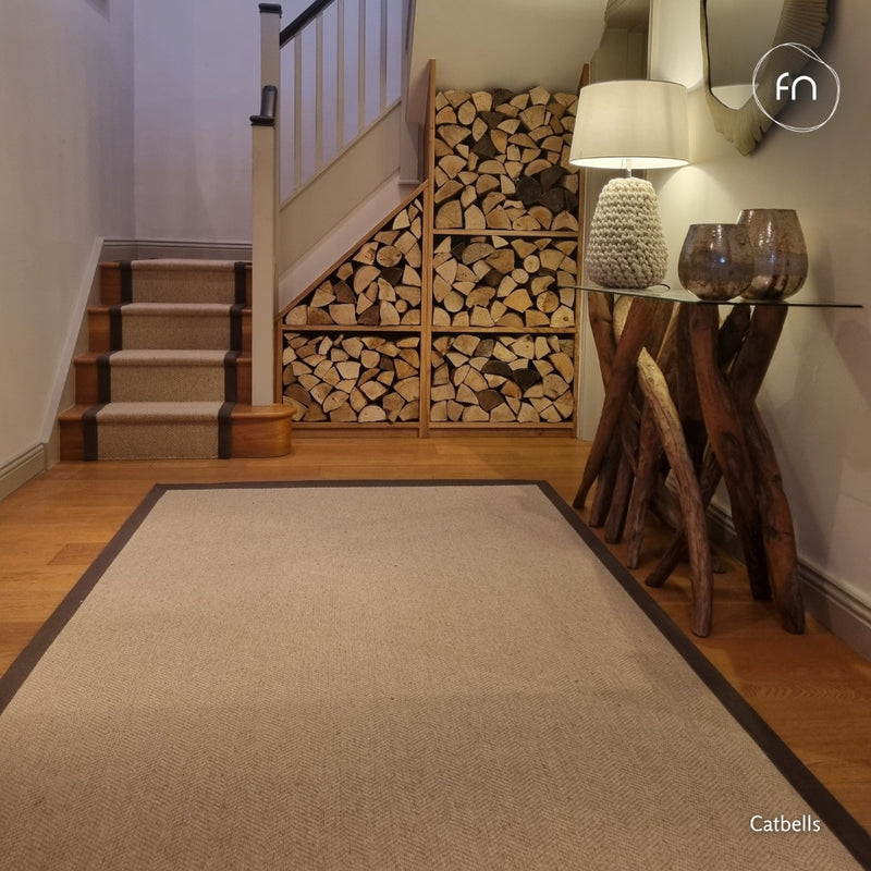 A rug in a light beige herringbone wool pattern with a brown border and a matching stair runner.
