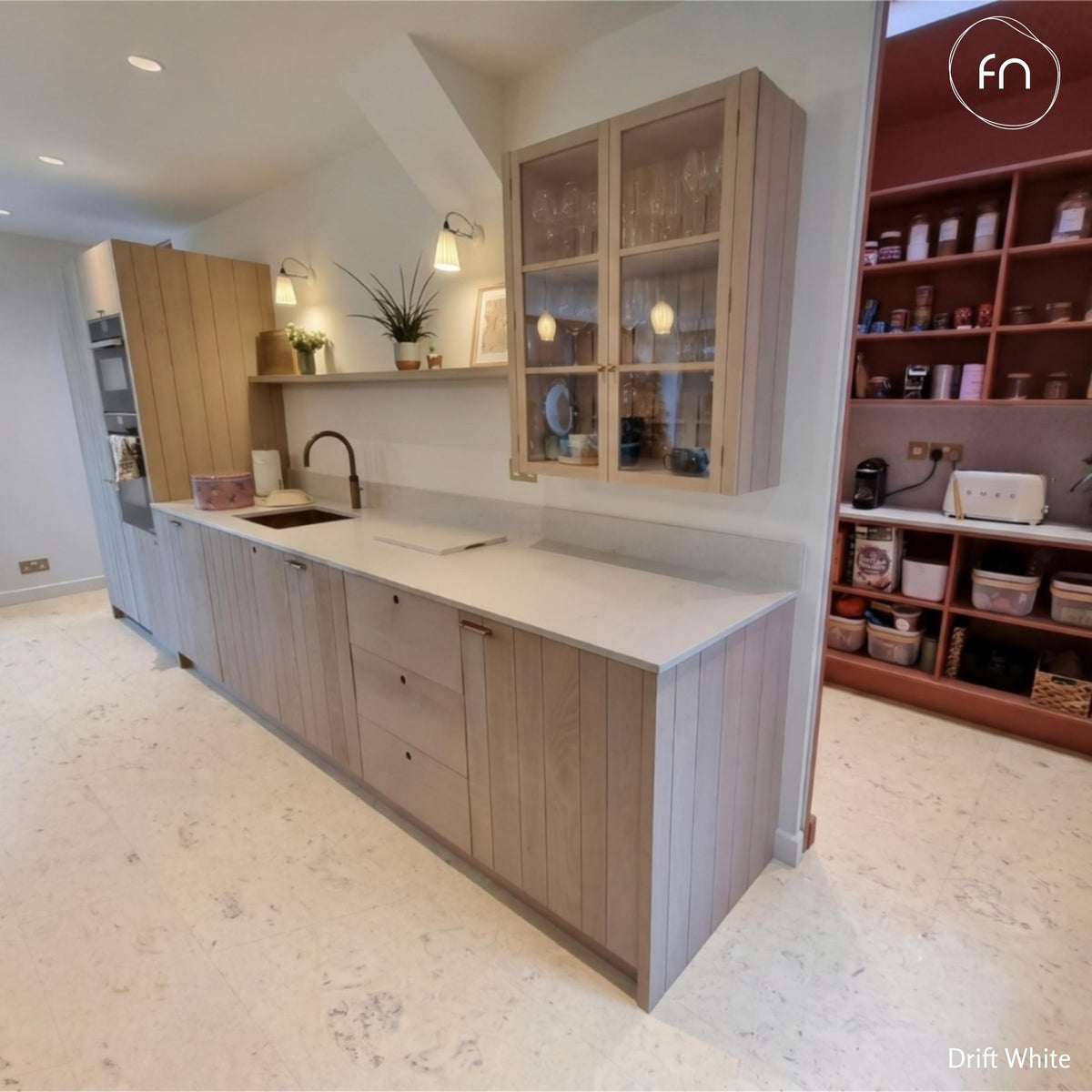 Modern kitchen with cork flooring, light wood cabinets and white countertops.