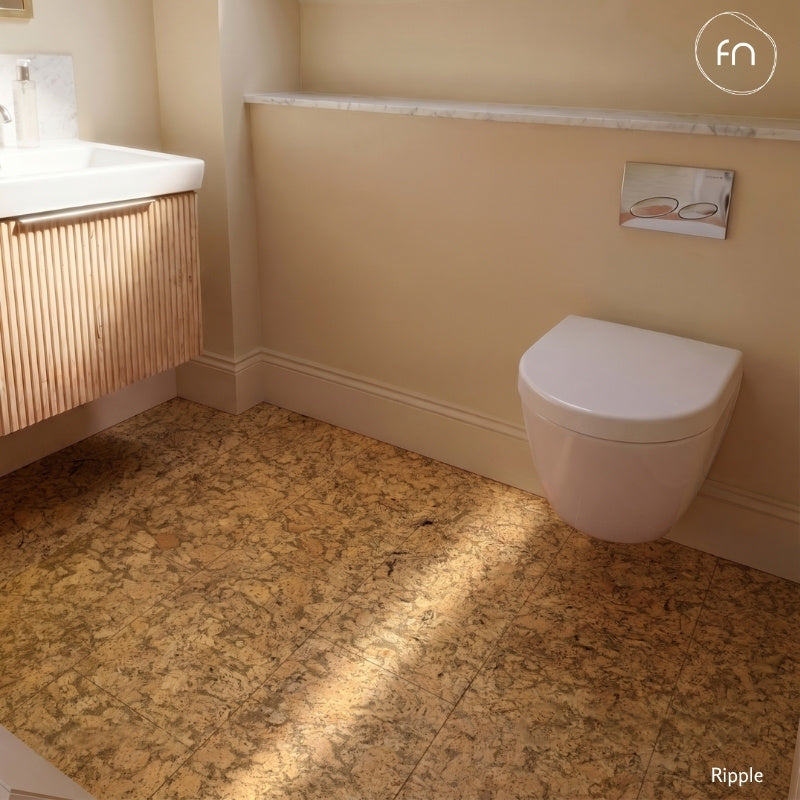 Bathroom with a cork tile floor and a white toilet and sink on a beige wall.